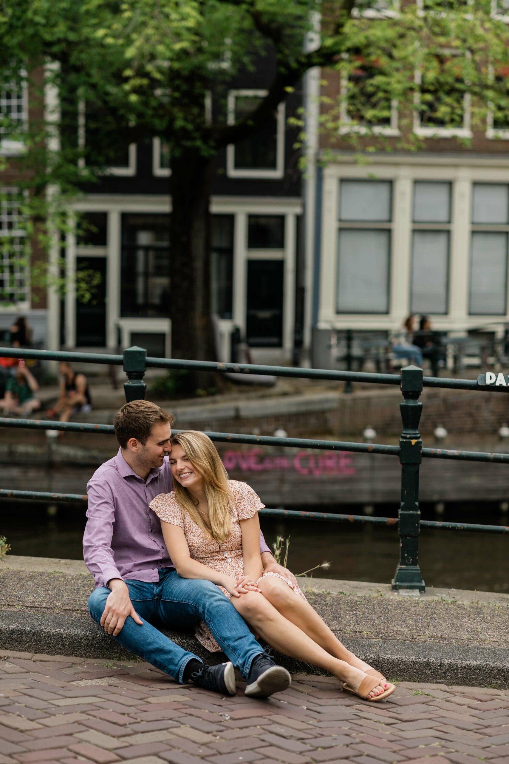 alt="romantic couple sitting by Amsterdam canal for candid photo"