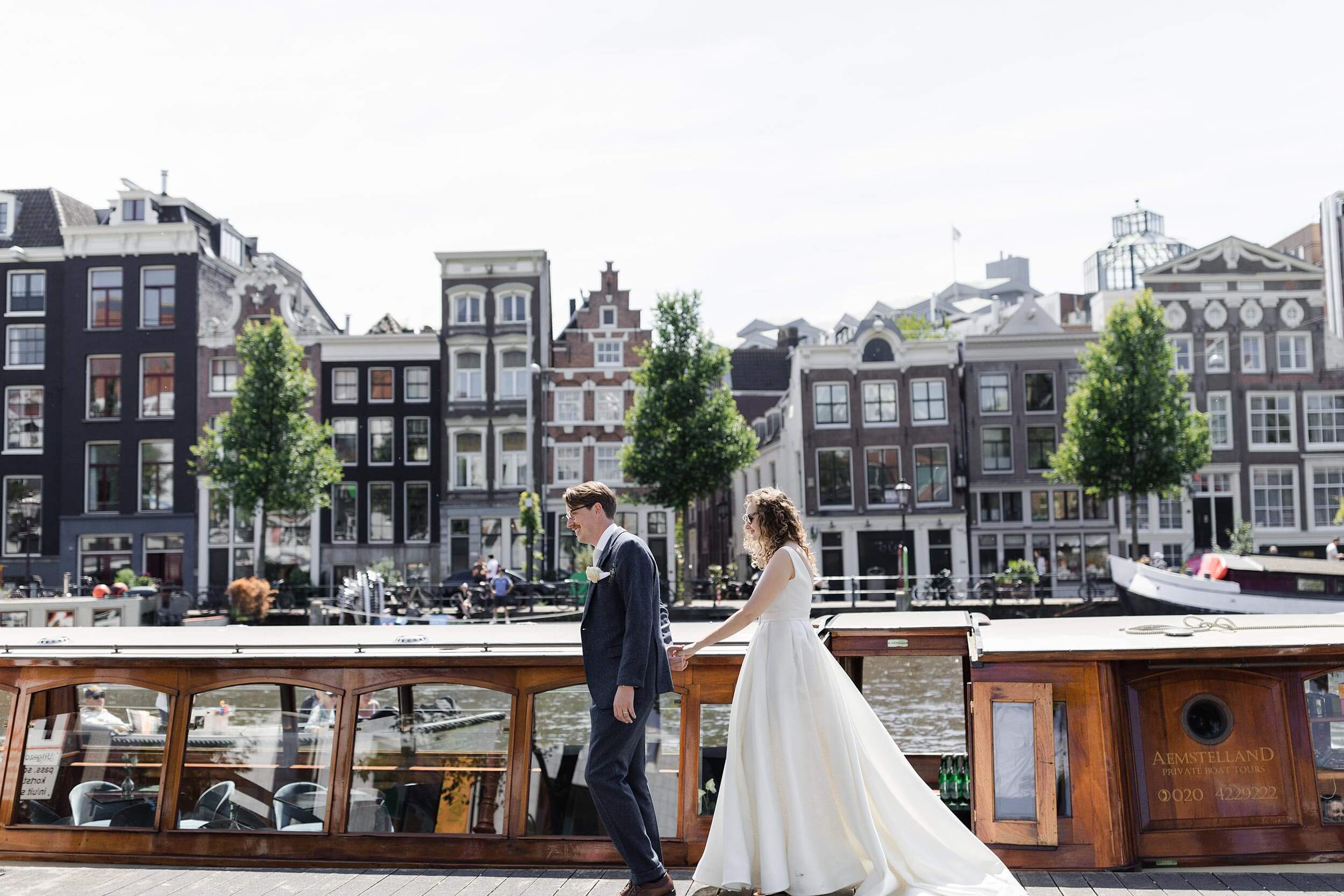 alt="Wedding of MJ & Matthew as they wait for the Canal Boat to pick them up on the River Amstel"